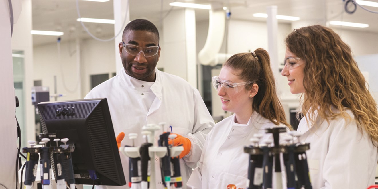 Three scientists in a GSK lab looking at a computer screen
