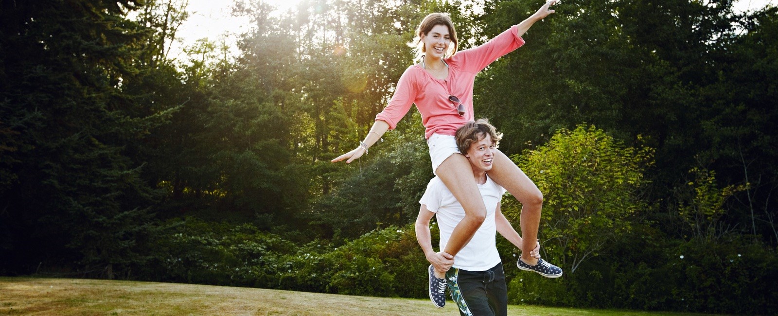 Woman sitting on man's shoulders, laughing