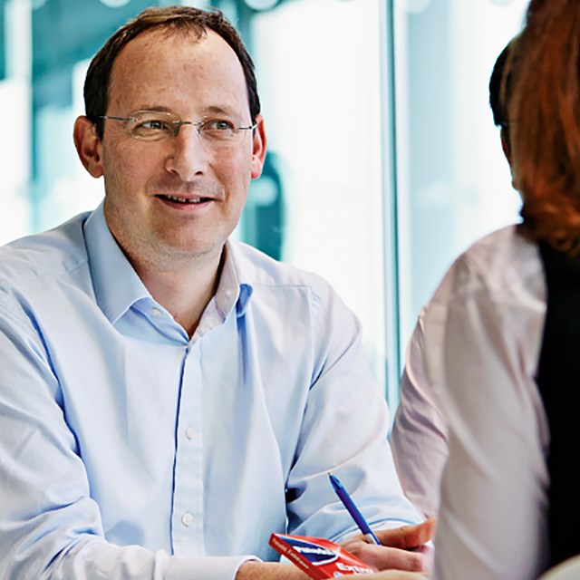 man talking to a woman holding a Panadol package