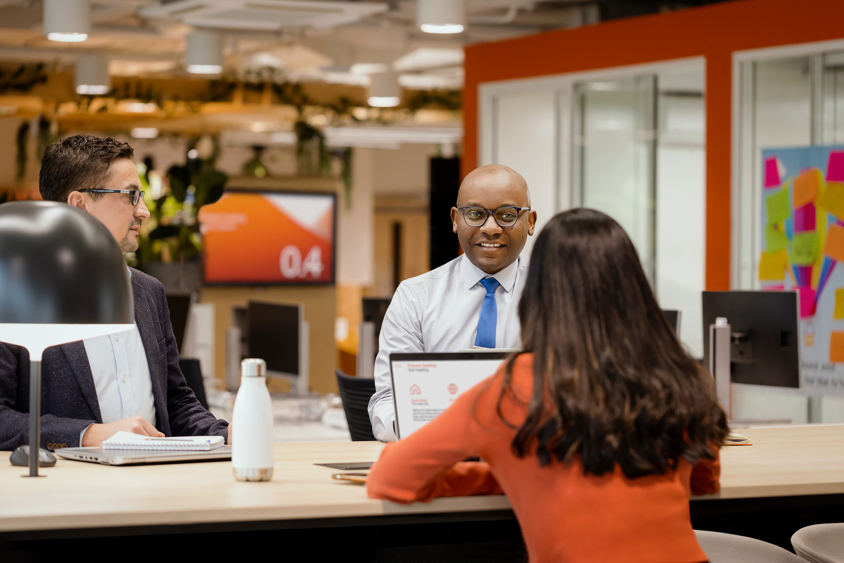 Two men and one woman sitting and conversing in the office