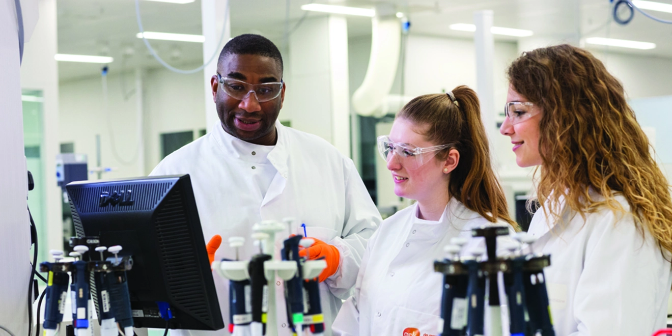 Three scientists in a GSK lab looking at a computer screen