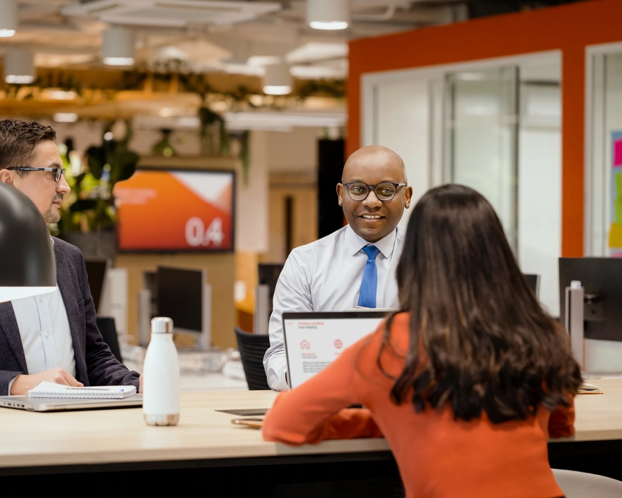 Two men and one woman sitting and conversing in the office